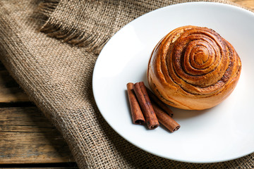 Sweet cinnamon roll with sticks on plate