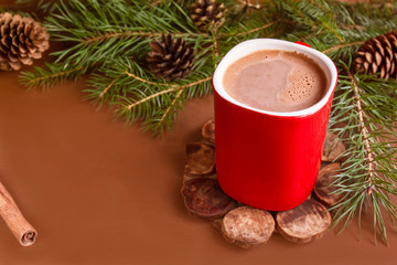 Christmas traditional hot drink cocoa in red cup, fir branches and cones on the dark wooden background copy space