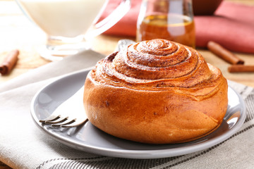 Sweet cinnamon roll and fork on plate