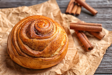 Sweet cinnamon roll on wooden table