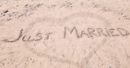 Text JUST MARRIED written on sand. Beach wedding concept