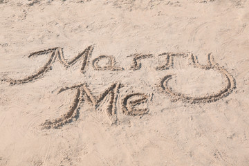 Text MARRY ME written on sand. Beach wedding concept