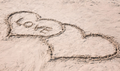 Drawing of hearts with word LOVE on sand. Beach wedding concept