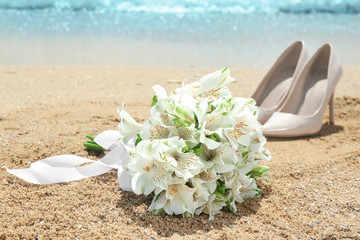 Beautiful bouquet and high heel shoes on sand. Beach wedding concept
