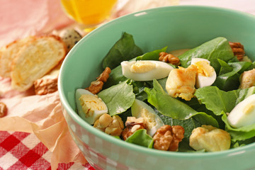 Salad with quail eggs and spinach in bowl on table
