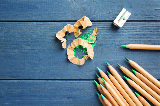 Green pencils with sharpener and shavings on wooden table