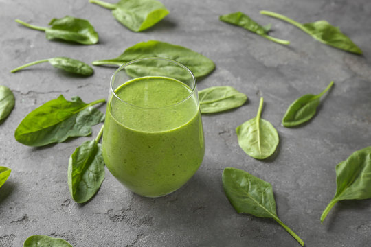 Glass of spinach smoothie on grey background