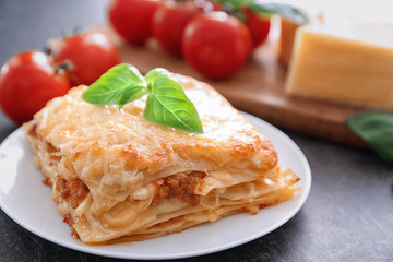 Plate with tasty lasagna on table, close up