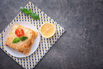 Plate with tasty lasagna on grey background
