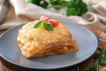 Plate with tasty lasagna on table