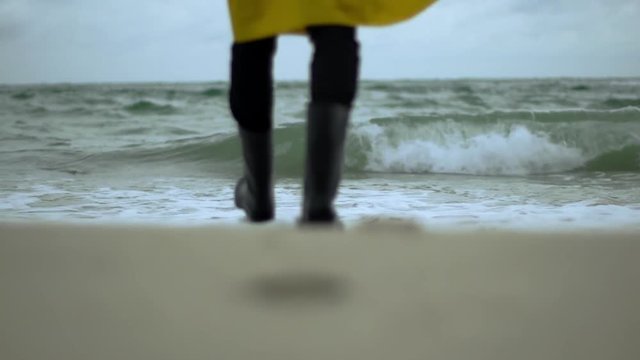 Person walking into water standing still in waves slow motion