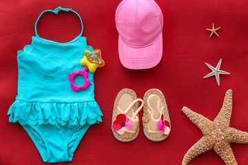 Composition with baby swimsuit on red background