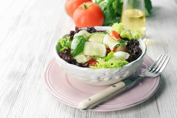 Healthy salad with cucumbers in bowl on table
