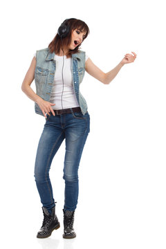Young Woman In Headphones Is Singing And Playing Air Guitar
