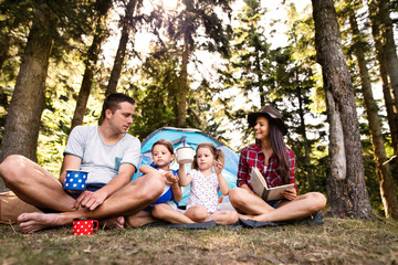 Fototapeta premium Beautiful young family with daughters camping in forest.
