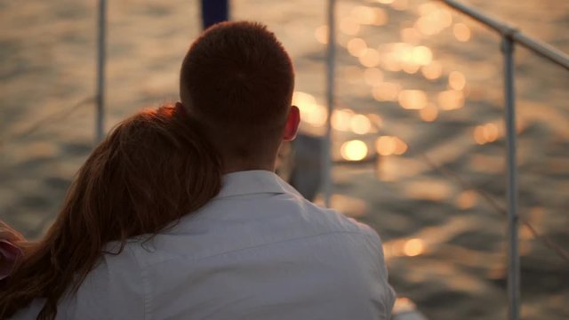 woman put head on men's shoulder while sitting on front of yacht watching at sea backside in slow motion