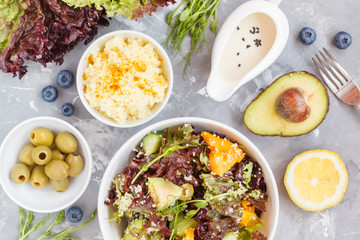 Bright colorful salad with couscous and vegetables, ingredients on the table, vegan lunch, top view.