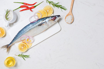 Fish dish cooking with various ingredients. Fresh raw fish decorated with lemon slices and herbs on wooden table.