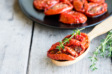 Bowl of sun dried tomatoes on wooden background. Sun dried tomatoes with olive oil and herbs