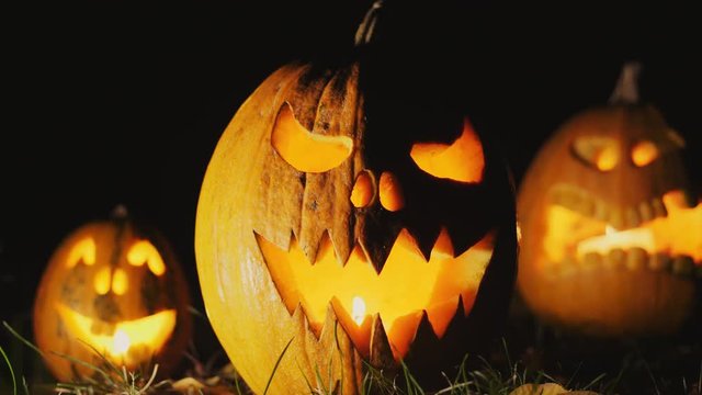 Halloween pumpkin head jack lantern with burning candles over black background. Halloween holidays art design, celebration