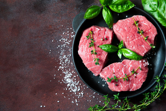 raw beef steak on a rust background with olive oil and spices