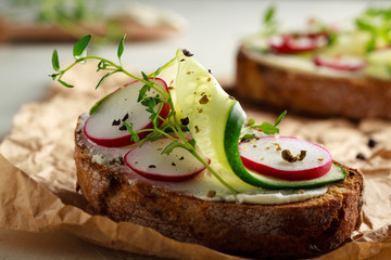 Sandwich with red radish, cucumber and fresh herbs and pepper.