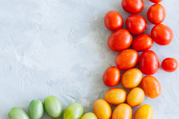 Bright colorful tomatoes cherry on a white stone background. Overhead view and copy space.