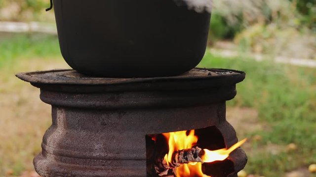 Cooking outdoors in cast-iron cauldron. Cooking on a fire. Food in a cauldron on a fire. Cooking food in nature on the cauldron.