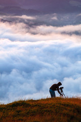 Photographer shooting natural phenomenon - the clouds that roam the mountains. Concept theme: nature, weather, tourism, extreme, healthy lifestyle, adventures. Unrecognizable persones.
