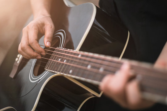 Guitar player playing acoustic guitar, close up