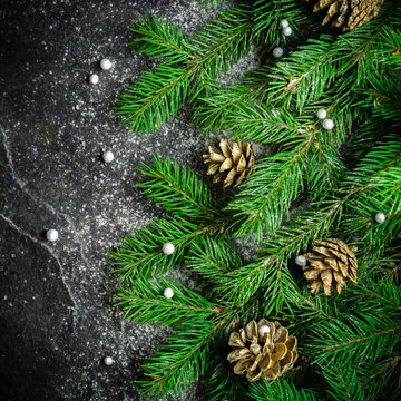 Christmas and New Year background. Christmas tree branch on a black background. Cones and fur-tree toys. View from above.