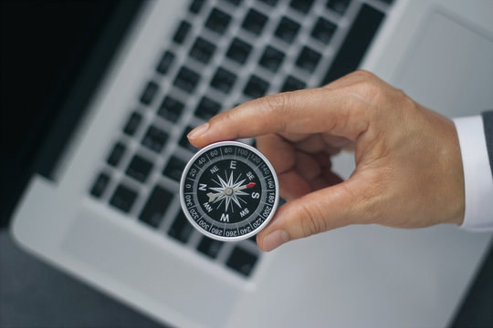 Businessman with a compass holding in hand on laptop background