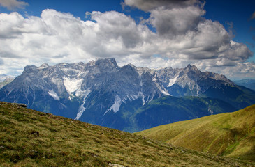 Green slopes of Carnic Alps main ridge and jagged Dreischusterspitze / Punta dei Tre Scarperi and Haunold / Rocca dei Baranci peaks in Sexten Dolomites, South Tyrol, Italy, Europe