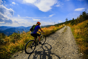 Obraz premium Cycling women riding on bike in autumn mountains forest landscape. Woman cycling MTB flow trail track. Outdoor sport activity.