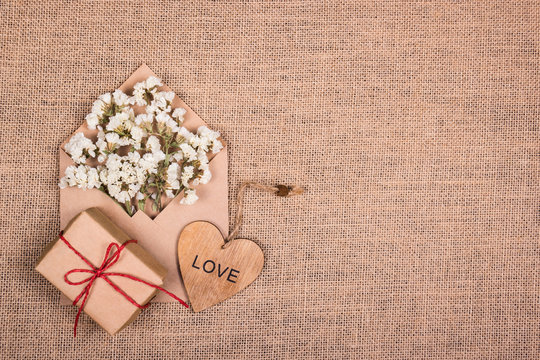 Wooden heart, white flowers in an envelope and a gift. Copy space