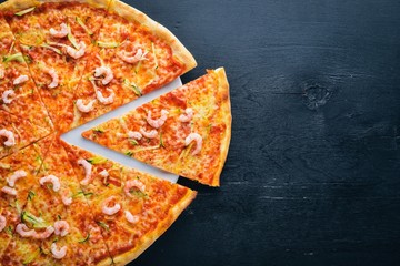 Pizza with shrimp. On a wooden background. Top view. Free space for text.