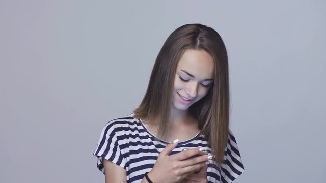 Teen girl using typing sms in smart phone smiling, locked down real time video
