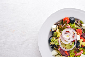 Greek salad. Fresh vegetables on a wooden background. Top view. Free space for text.