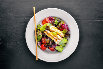 Vegetable salad with chicken and mango sauce on a wooden background. Top view. Free space for text.