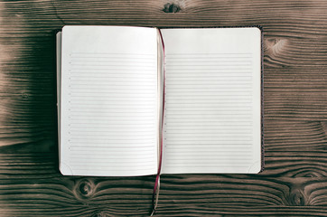 Open diary book with empty pages on burnt table surface.