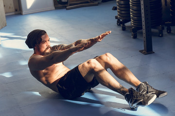 Handsome muscular man doing sit-ups on gym floor