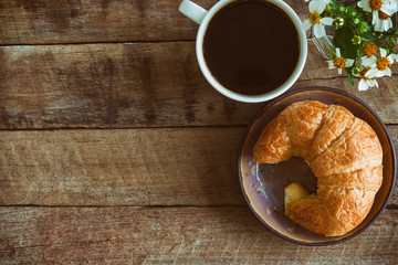 Homemade croissant served with black coffee or americano. Delicious breakfast with fresh croissant and coffee. Croissant and black coffee and chamomile with copy space in top view or flat lay style.