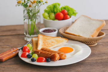 Homemade breakfast with sunny side up fried egg toast sausage fruits vegetable strawberry jam in side view with copy space.Delicious homemade american breakfast concept for background or wallpaper.