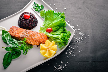 Baked salmon fillet with wild rice. On a wooden background. Top view. Free space for text.