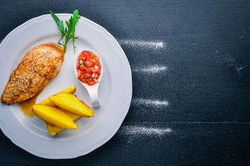Chicken steak and potatoes on a wooden background. Top view. Free space for text.