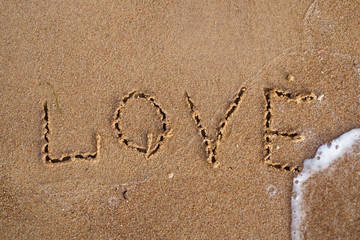Top view of word love written on sand beach with wave of the sea. Beach background