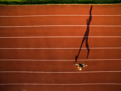 Shot Of A Young Male Athlete Training On A Race Track. Sprinter Running On Athletics Tracks Seen From Above.