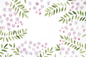 Frame of lilac flower petals, green leaves with space for text on white background. Flat lay, top view