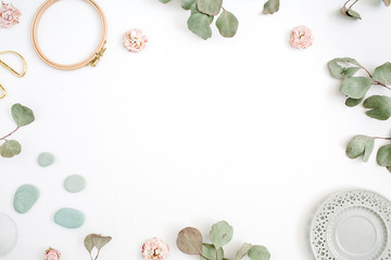 Flat lay border frame with eucalyptus branches, plate on white background. Top view floral background with space for text.