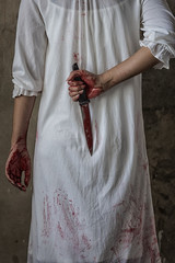 Woman holding knife back on her hand with blood